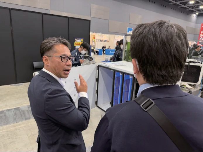 展示会で来場者に自社製品を説明する社員