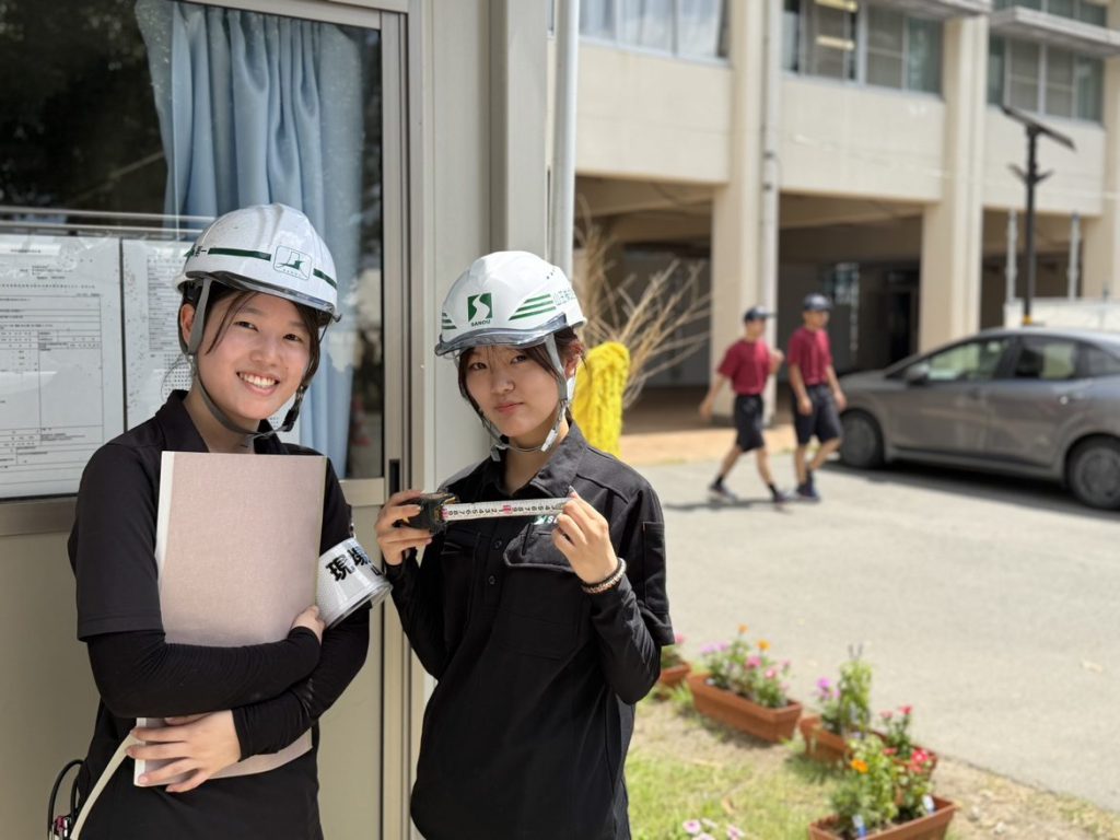建築現場でヘルメットを着けて働く社員の様子
